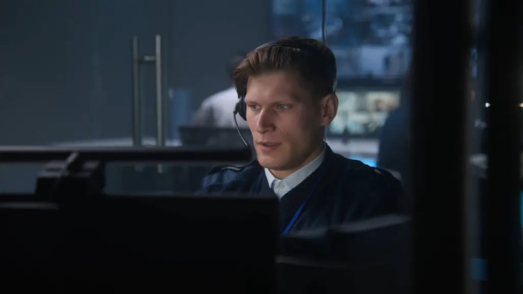 Air traffic controller working at a monitoring station with a headset, focused on screens in a control room environment