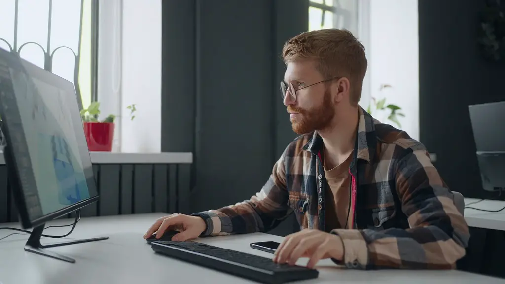 Young man working on a desktop computer in a modern office, focusing on digital design work, symbolizing creative and freelance career paths