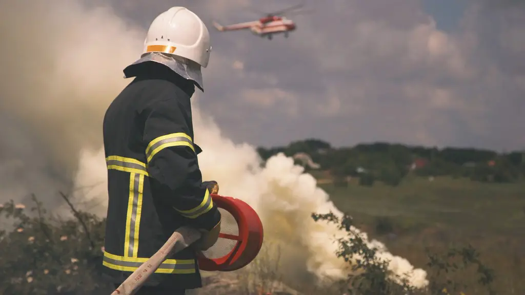 Firefighter in full gear standing near smoke with a helicopter overhead, representing public service careers